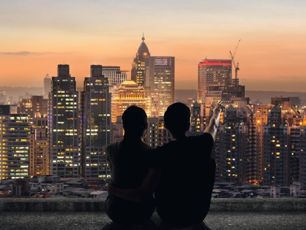 Silhouette of couple sit on ground point faraway on the roof above the city in the night.